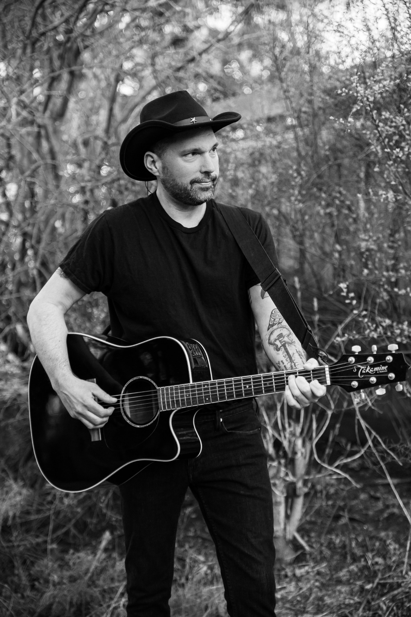 Black-and-white portrait of Lance Clyne holding an acoustic guitar